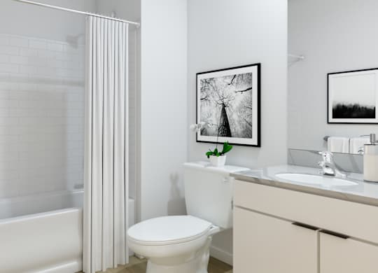 A white bathroom with a toilet, sink, and a framed picture on the wall.