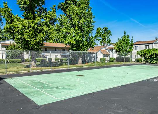 A tennis court surrounded by a fence and trees.
