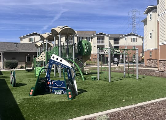 A playground with a green slide and a white and blue play structure.