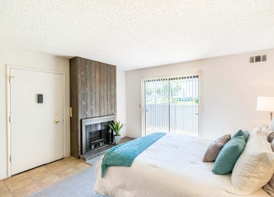 A bedroom with a large bed and a fireplace. at Chaparral Apartments, California, 93551