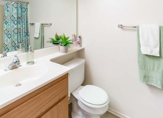 A white toilet sits in a bathroom next to a sink at Chaparral Apartments, California