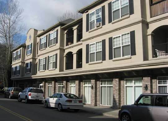 A row of townhouses with cars parked in front.