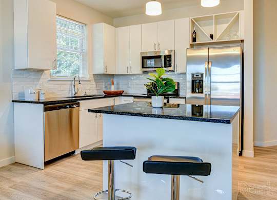 a kitchen with white cabinets and a counter with stools at Solo at North Bergen, North Bergen, NJ