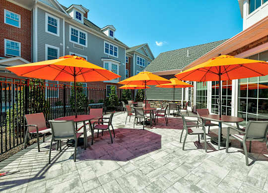 a patio with tables and chairs and umbrellas  at Solo at North Bergen, North Bergen, New Jersey