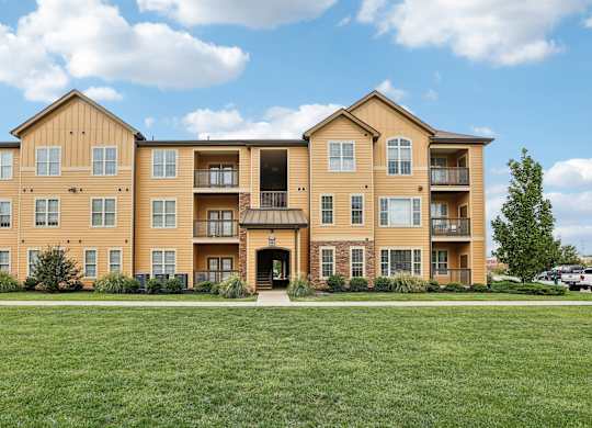 a large apartment building with a green lawn