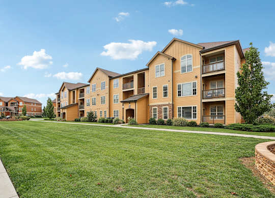 the view of an apartment building with a green lawn
