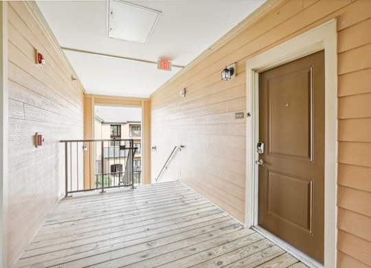 the entrance to a condo with a wooden floor and a brown door