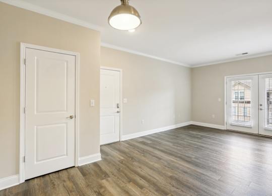 an empty living room with white doors and a window
