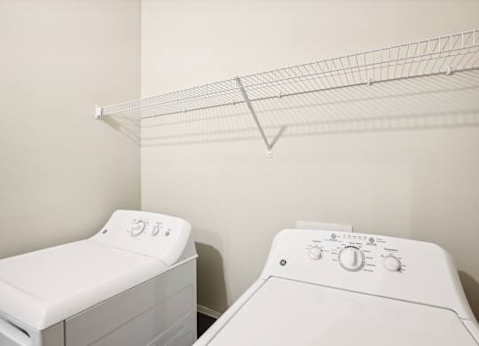 a washer and dryer in a laundry room with a rack on the wall