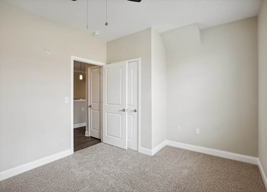 an empty bedroom with white doors and a door to a closet
