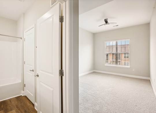 an empty bedroom with white doors and a window
