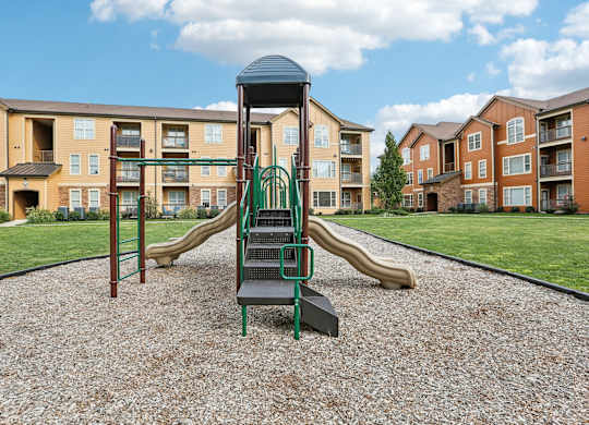 a playground with slides in front of an apartment complex