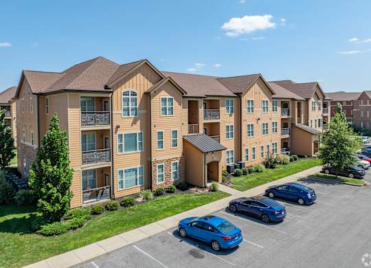 an apartment building with cars parked in a parking lot
