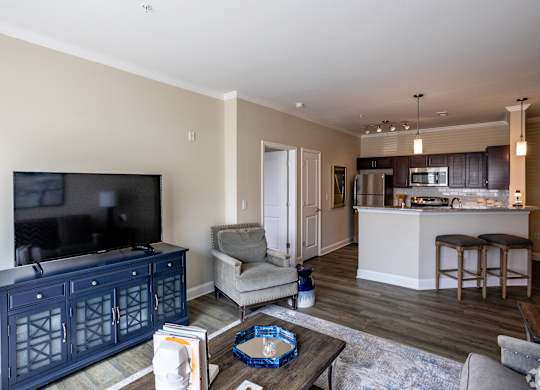 a living room with a tv and a kitchen with a bar and a table