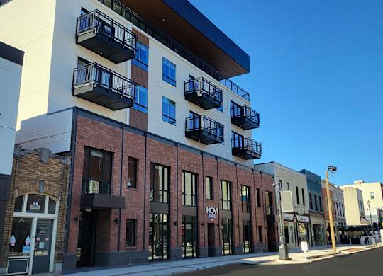 Exterior of Novi Lofts with balconies and rooftop restaurant space overlooking Market Street in downtown Concord, NC