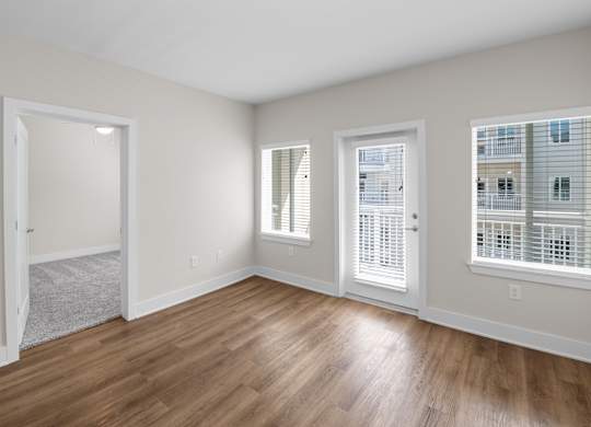 A room with wooden floors and three windows.