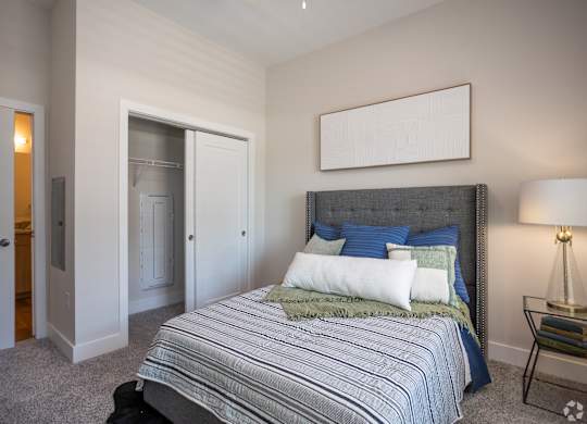A bedroom with a bed, a nightstand, and a lamp.
