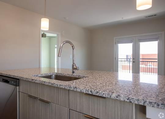 Modern kitchen with a granite countertop and stainless steel appliances at NOVI at Concord - luxury apartments in Concord, NC.