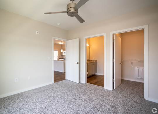 A room with a ceiling fan and carpeted floor.