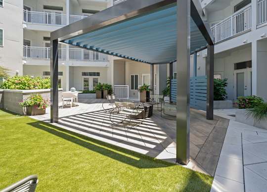 A patio with a table and chairs is covered by a blue awning.