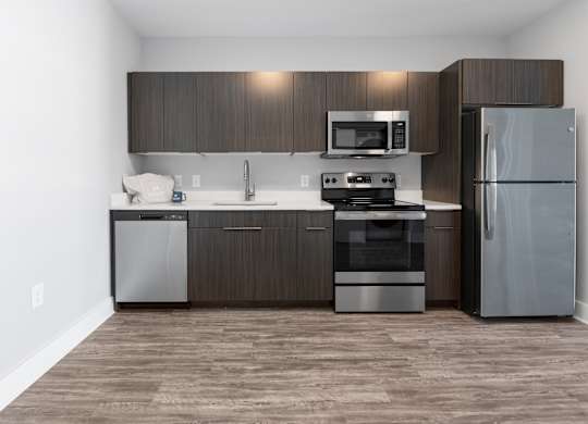 A modern kitchen with dark wood cabinets and stainless steel appliances.