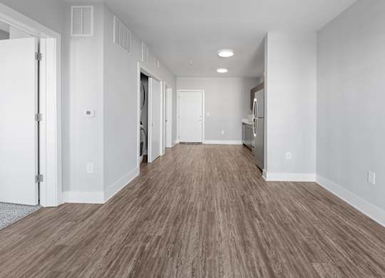 A long hallway with wood flooring and white walls.