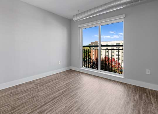 A room with a window overlooking a building with trees.
