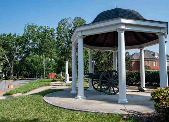 A gazebo with a cannon sits in a grassy area.