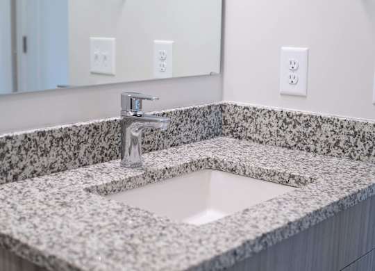 A bathroom sink with a granite countertop and a silver faucet at Novi Rise.