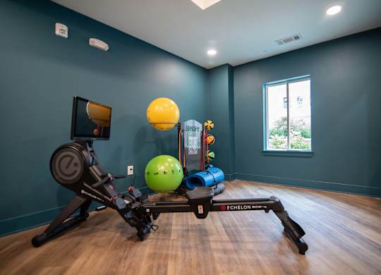 A room with a rowing machine and exercise equipment at Novi Rise's fitness center