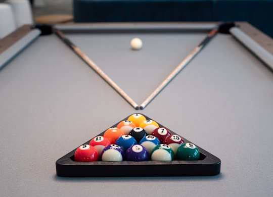A pool table with a white ball in the air and a cue stick in the middle.