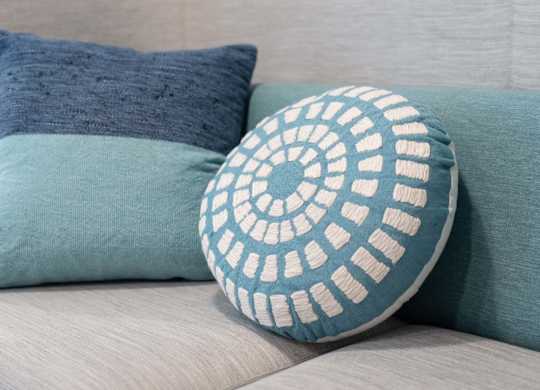 A decorative pillow with a white pattern is placed on a couch.