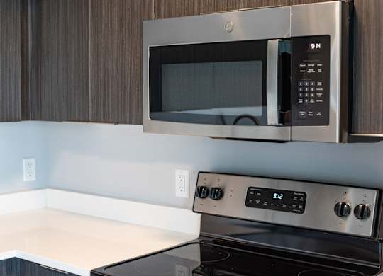 A modern kitchen with a stainless steel microwave above a stove at Novi Flats Apartments in Concord, NC