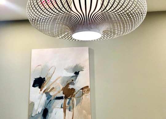 A modern art piece with a painting and a lamp hanging from the ceiling.