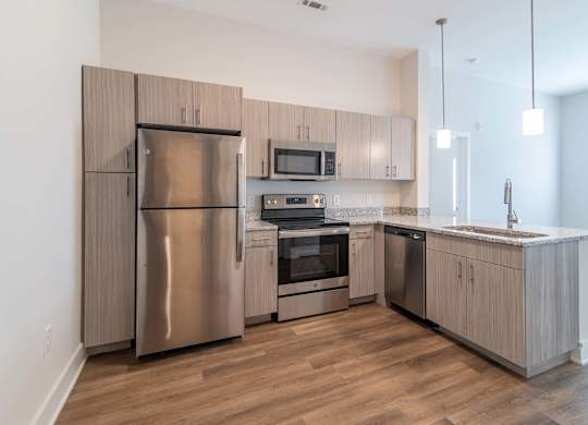 A modern kitchen with stainless steel appliances and granite countertops at Novi Rise in Concord, NC