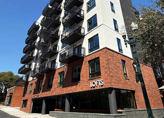 A tall building with a white top and a red base with the word "LOFIS" on it.