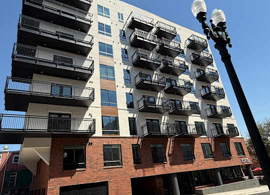 A tall building with balconies and a street lamp in front.