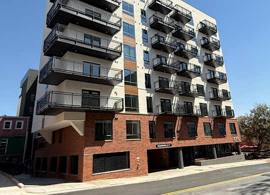 A modern multi-story building with balconies on the upper floors.