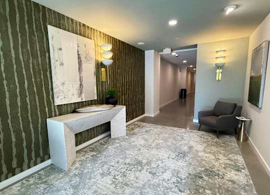 A hallway with a bench, a chair, and two paintings on the wall.