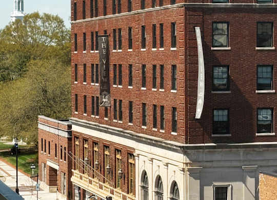 A tall brick building with a white steeple in the background.
