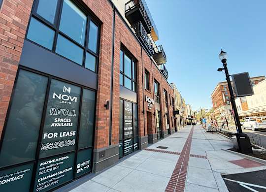 A street view of a building with a sign that says "NOVI RETAIL SPACES AVAILABLE FOR LEASE".
