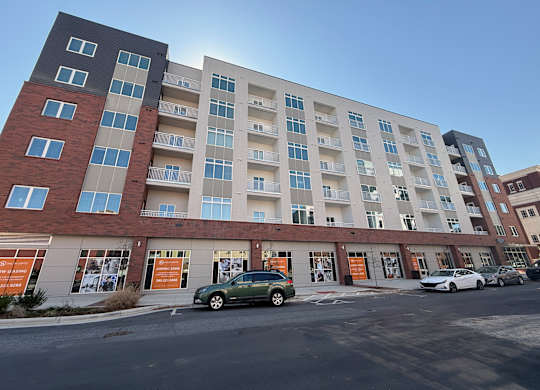 A multi-story apartment building with cars parked in front.