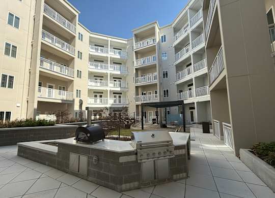 A modern courtyard with a fire pit and apartment buildings in the background.