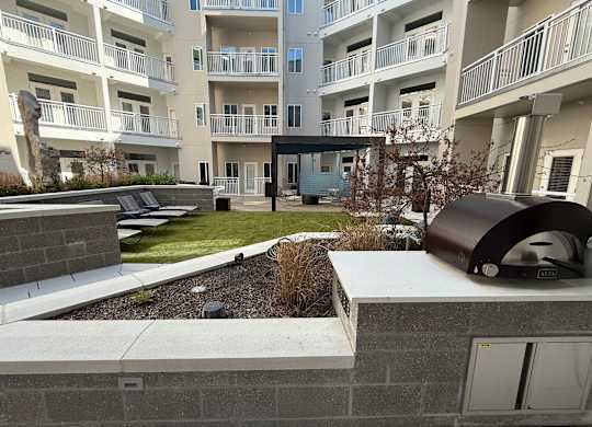A modern apartment complex with a landscaped courtyard and a BBQ grill.