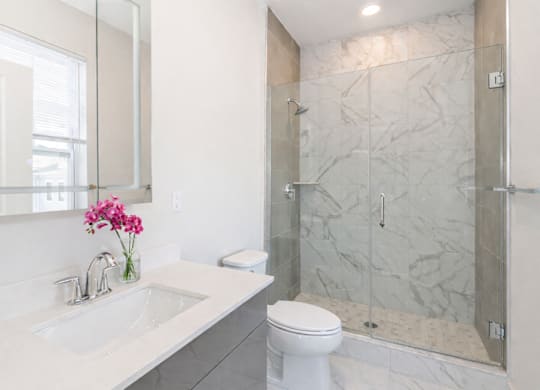 Modern apartment bathroom with glass shower and marble tile at The Rail North Bergen