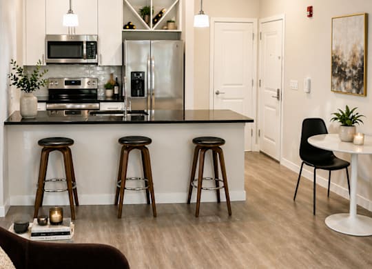 A modern kitchen with a bar area and a dining table at the Rail North Bergen.