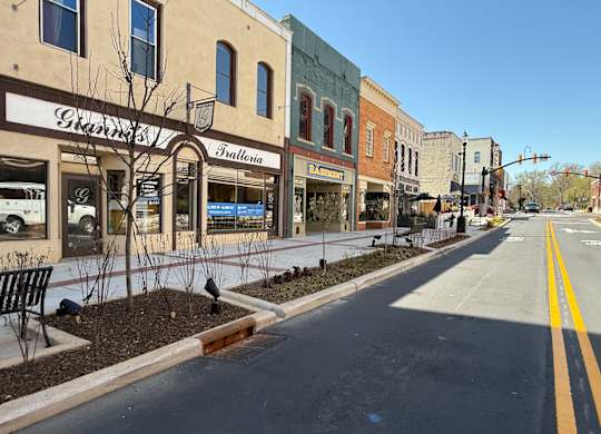 A street view of a small town with a few buildings and a bench.