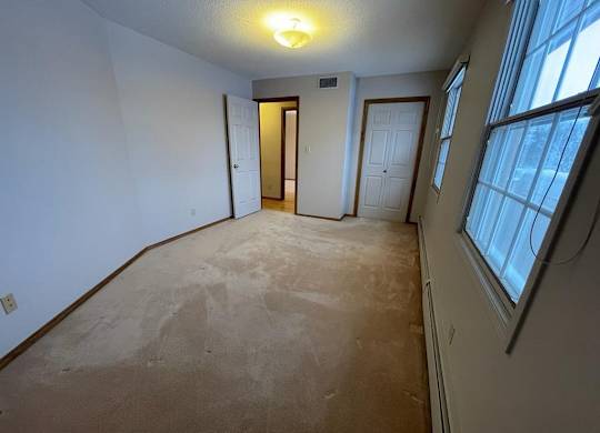 A room with a carpeted floor and a window on the right side.