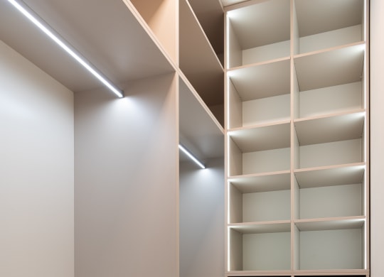 a walk in closet with white shelving and a wood floor