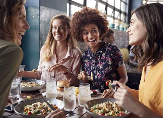 Four women are sitting at a table eating food.